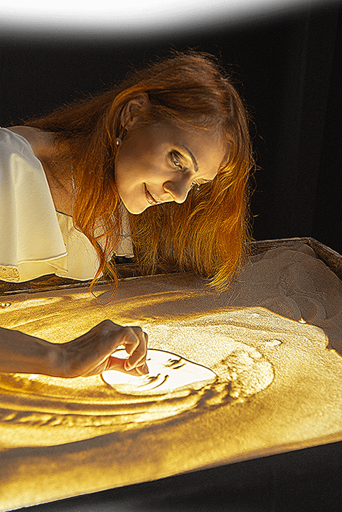 Sand animation artist Daria Tym creating a live sand painting performance.